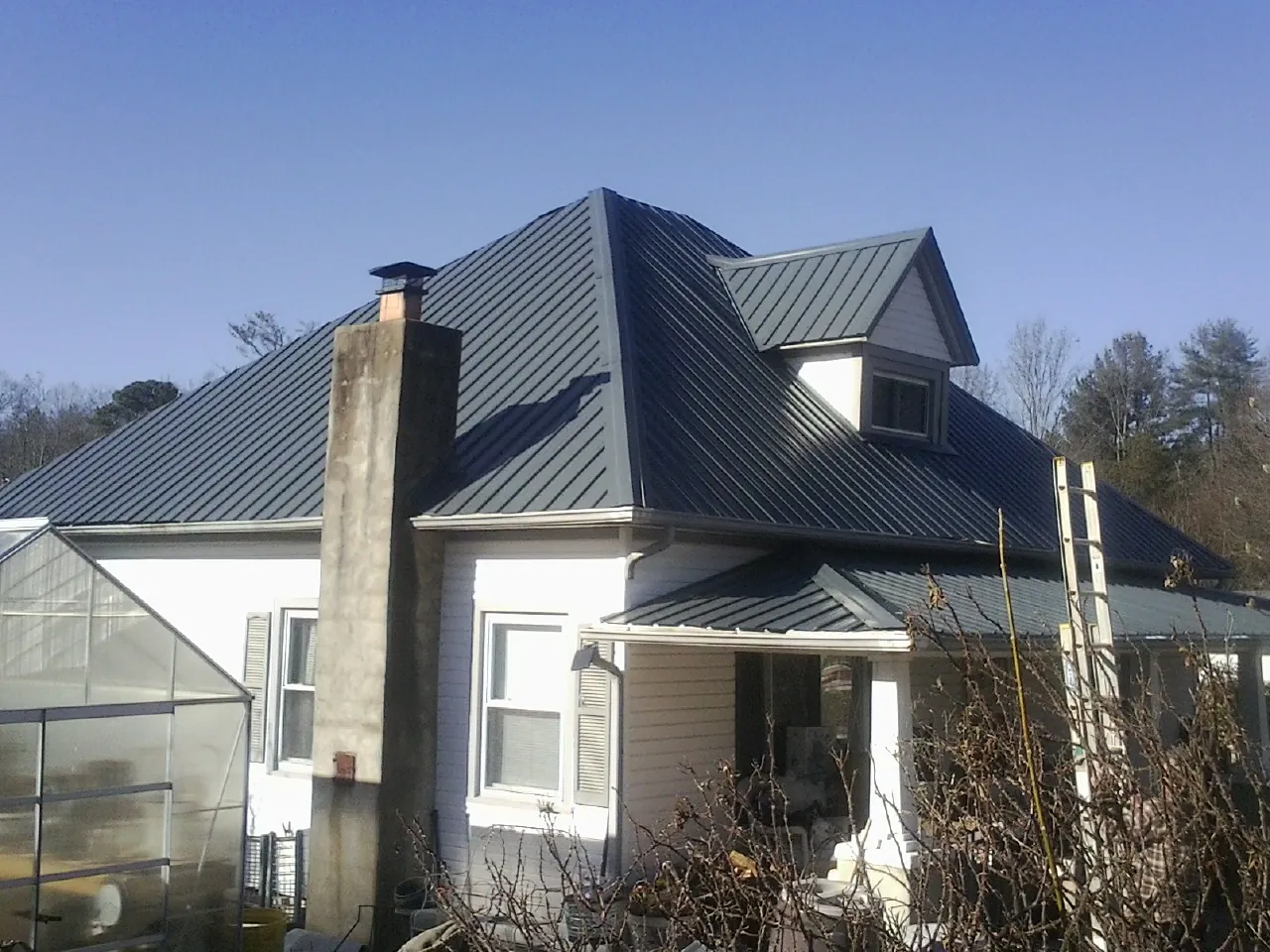Dark blue standing seam metal roof on a white farmhouse with dormer — Slate & Tile Roof Repair by Roofing Brothers in Perkasie