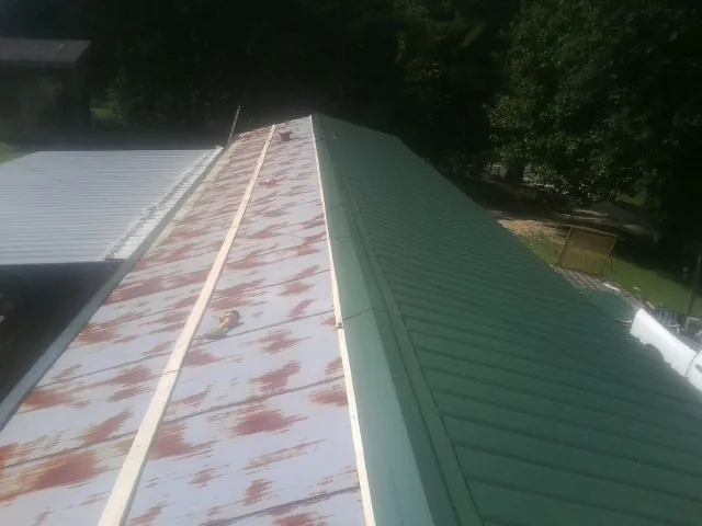 Old rusted panels beside newly installed green metal roofing — Wind Damage Roof Repair by Roofing Brothers in Perkasie