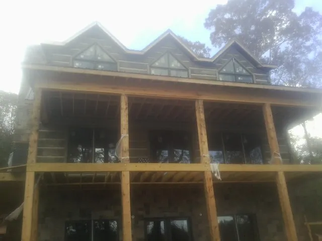 Dormers and porch framing on a large log home under construction — Roof Coating work by our crew in Perkasie