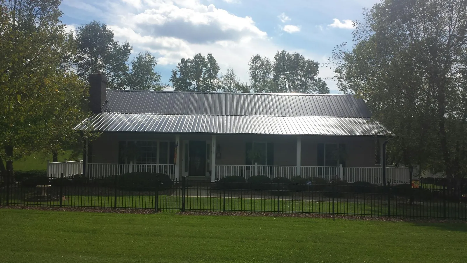 Gray metal roof on a brick ranch with a full width front porch — Gutter Guard Installation work by our crew in Perkasie