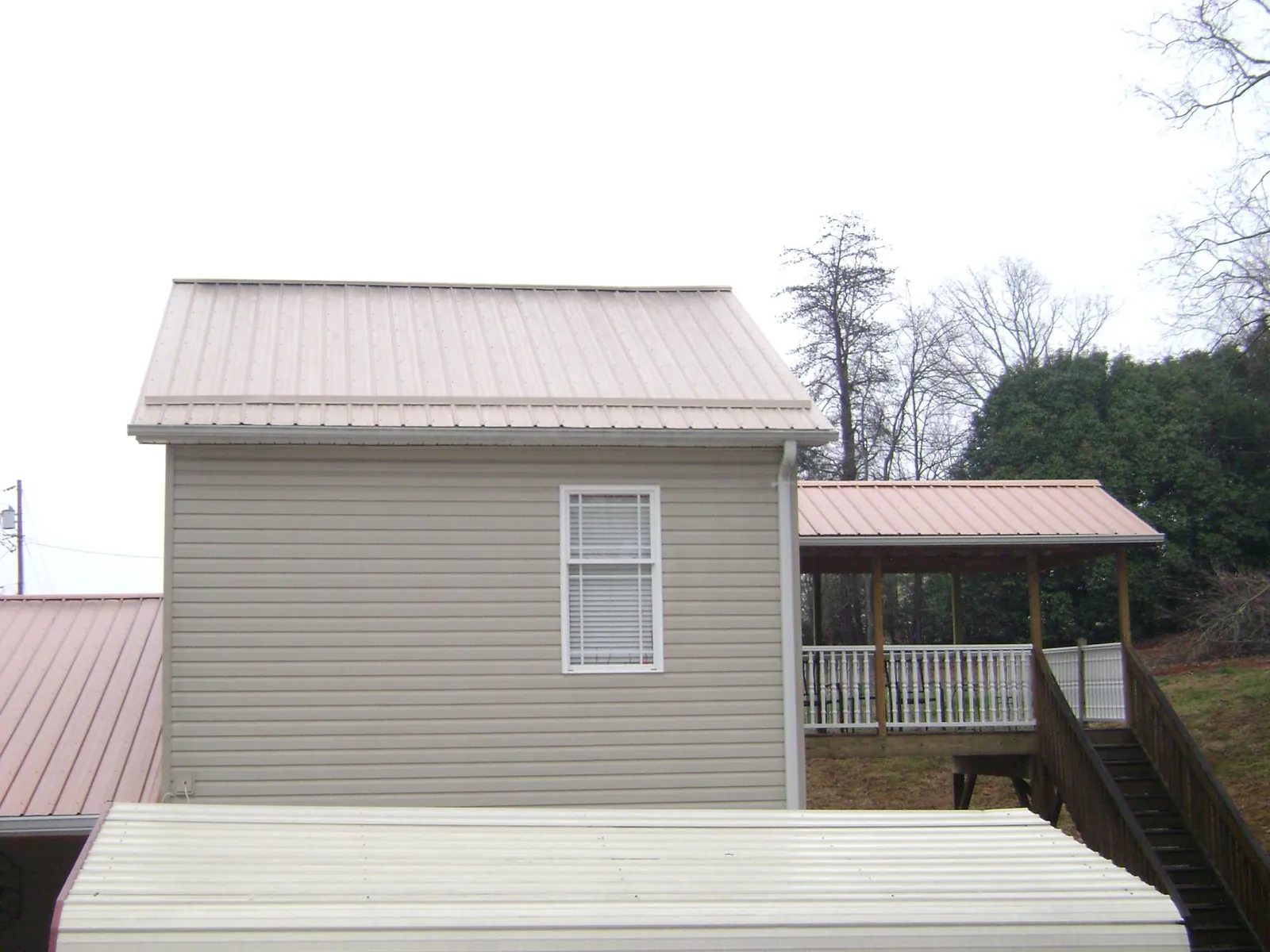 Tan metal roofs on a two story addition and attached porch, from a Roof Replacement job in Perkasie