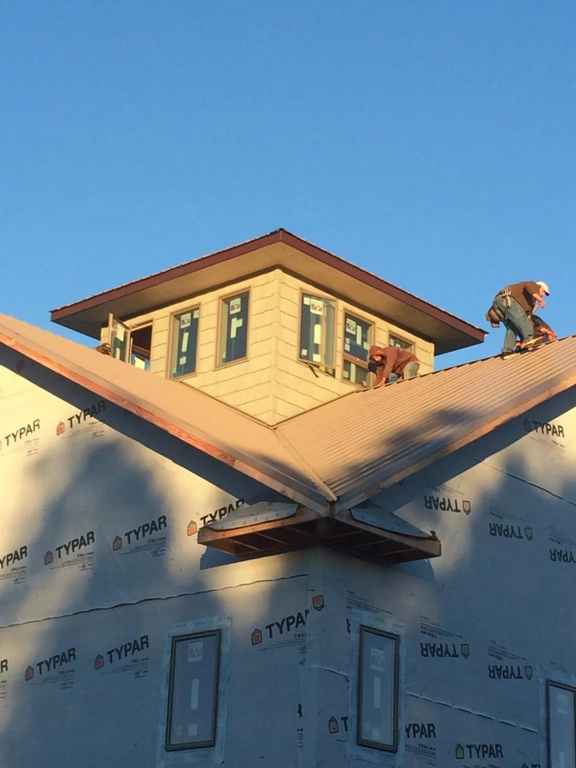 Roofers working around a rooftop cupola on a new metal roof at sunset — Roof Waterproofing in Perkasie by Roofing Brothers